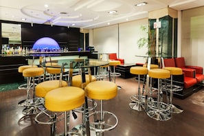 A bar area with stools and a glass table, surrounded by red and yellow seating. - Crowne Plaza Toluca Lancaster by IHG (Toluca)