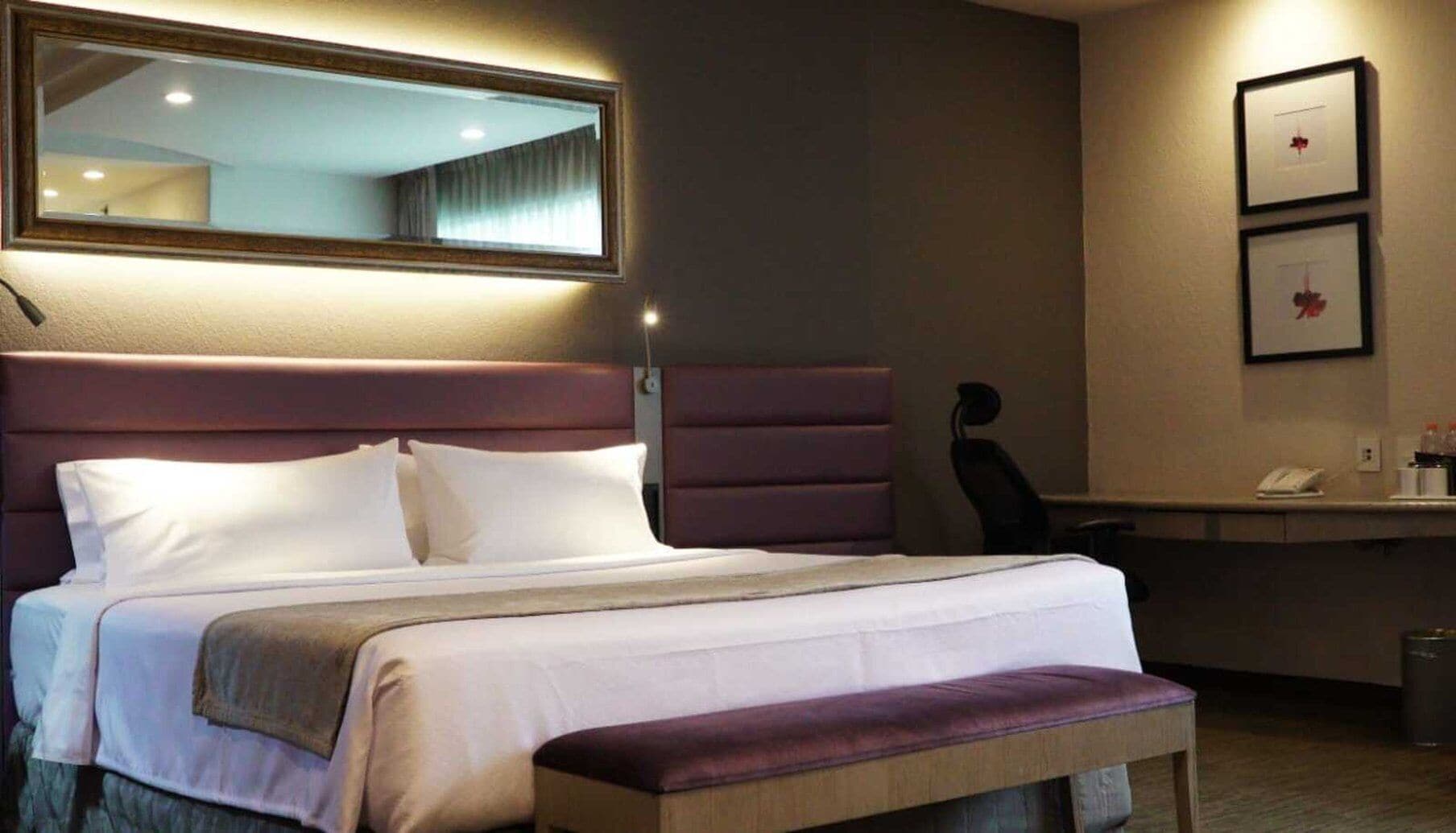 A hotel room with a large bed, a desk, and a chair.