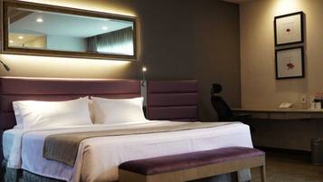 A hotel room with a large bed, a desk, and a chair.