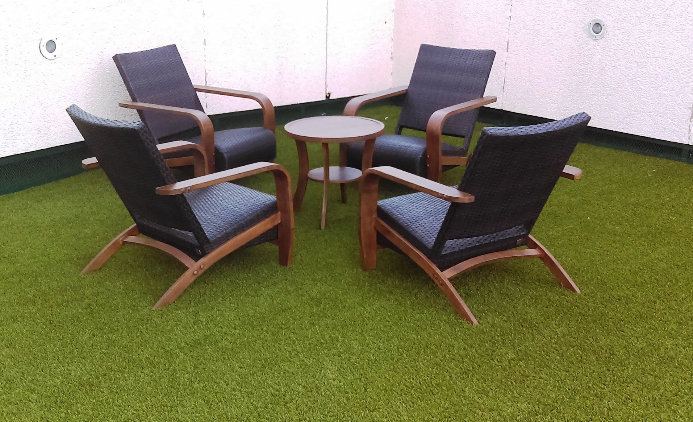 A set of four chairs and a small round table on artificial grass.
