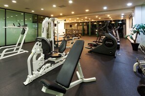 Un gimnasio con diversos equipos de ejercicio, que incluye una prensa de banca, una prensa de piernas y una caminadora.