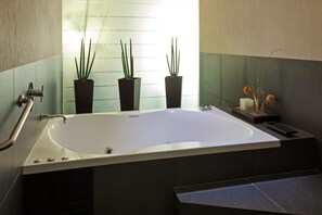 Un baño moderno con una bañera grande, plantas en macetas y una ventana que proporciona luz natural.