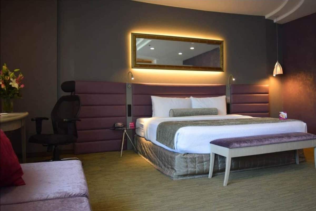 A modern hotel room with a large bed, a desk, and a chair.