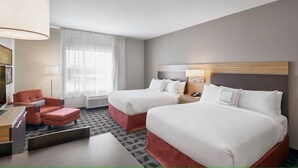 Une chambre d’hôtel avec deux lits, un bureau, une chaise et une fenêtre avec des rideaux.