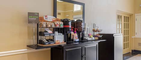 Estação de pequeno-almoço para levar, com máquinas de café, chocolate quente e diversas opções de comida.