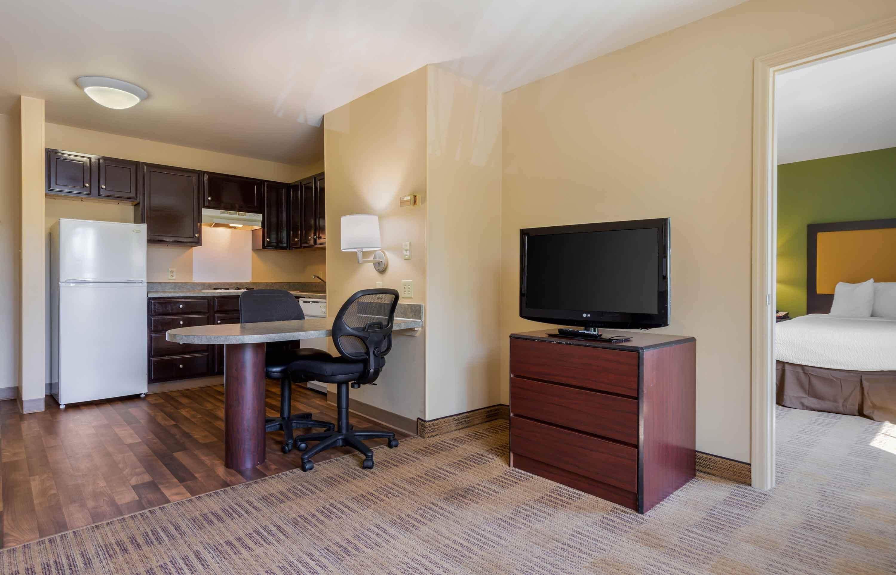 Une chambre d’hôtel compacte comprenant un coin cuisine, un bureau avec une chaise, une télévision et un lit.