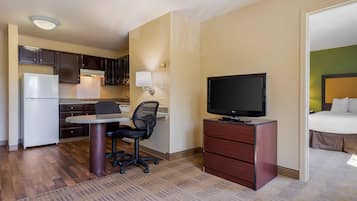 Une chambre d’hôtel compacte comprenant un coin cuisine, un bureau avec une chaise, une télévision et un lit.