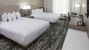 Habitación de hotel con dos camas, un escritorio, una silla y un televisor.