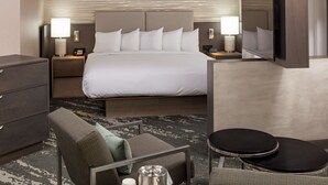 A hotel room with a large bed, bedside tables with lamps, a TV, a small sofa, and a coffee table.