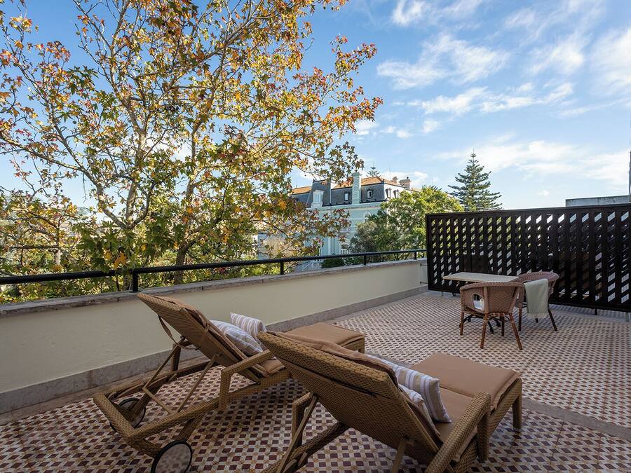 A balcony with wicker furniture, a table, and chairs.