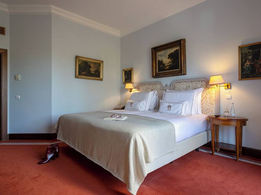 Una habitación de hotel con una cama grande, dos mesitas de noche y tres cuadros enmarcados en las paredes.