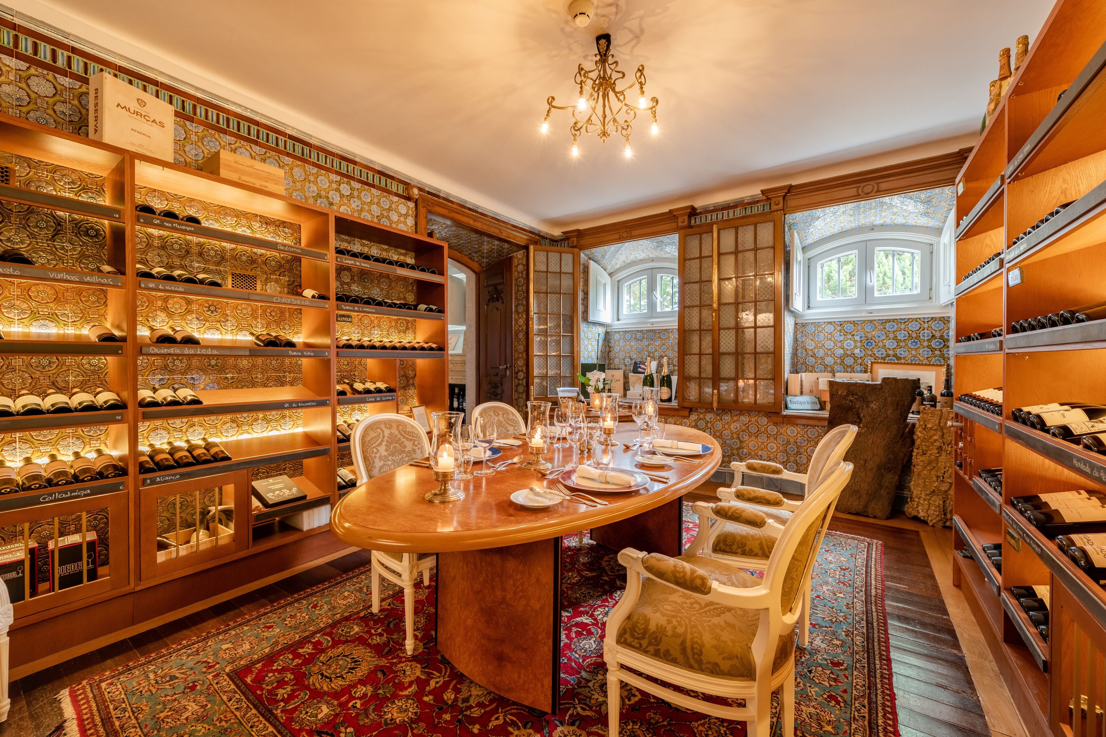 A luxurious wine cellar with wooden shelves, a large round table, and ornate chairs.