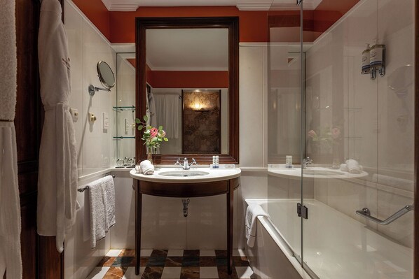 Un baño moderno con un lavamanos redondo, un espejo grande y una ducha con mampara de vidrio.