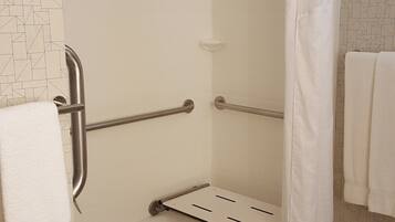 A shower area with a grab bar, a white shower curtain, and a towel rack.