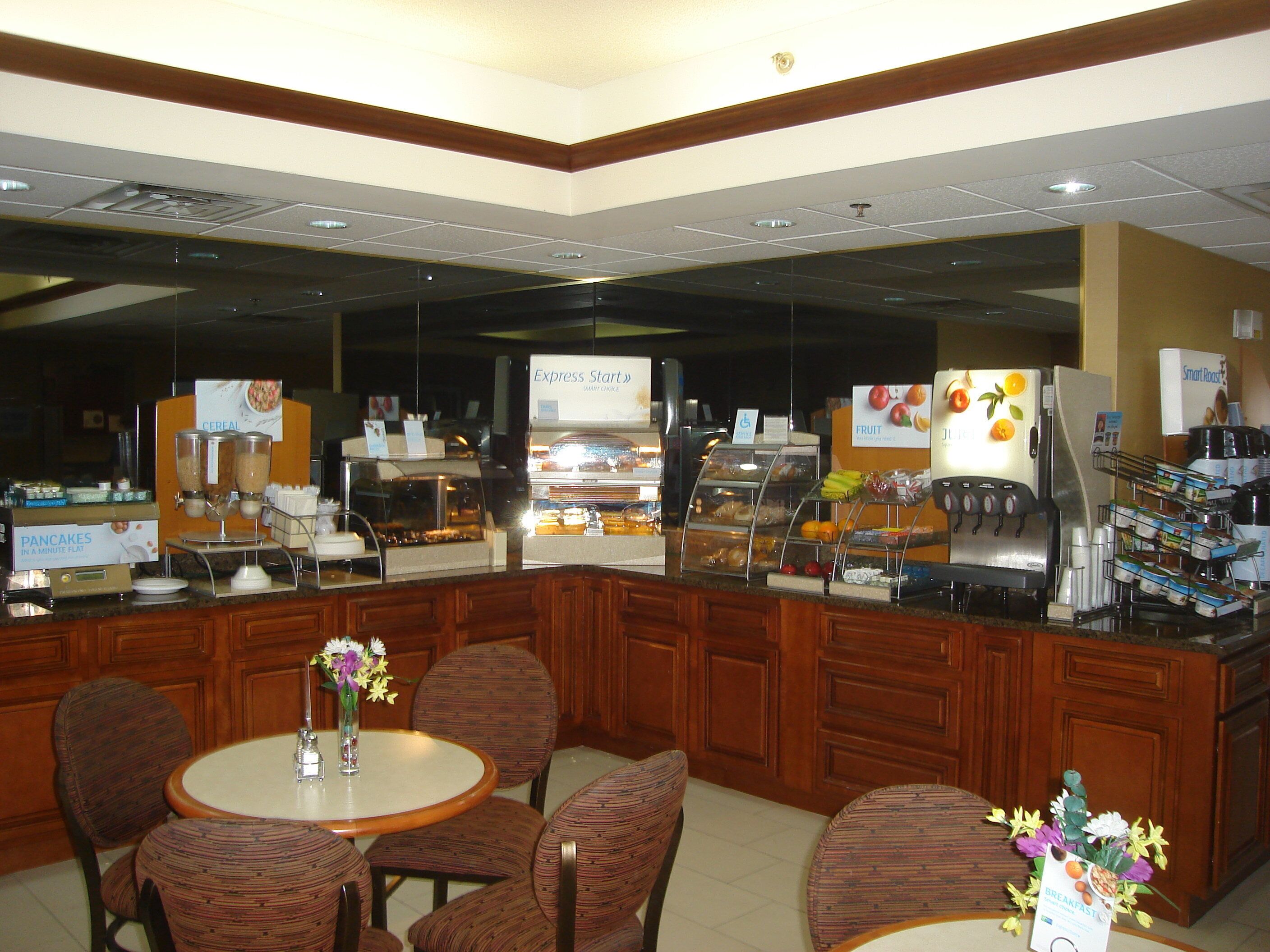 A breakfast bar with various food options, seating area with chairs, and a coffee machine.