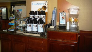 A coffee station with multiple coffee dispensers, a water cooler, and a fruit dispenser. - Holiday Inn Express Louisville Northeast by IHG (Louisville)