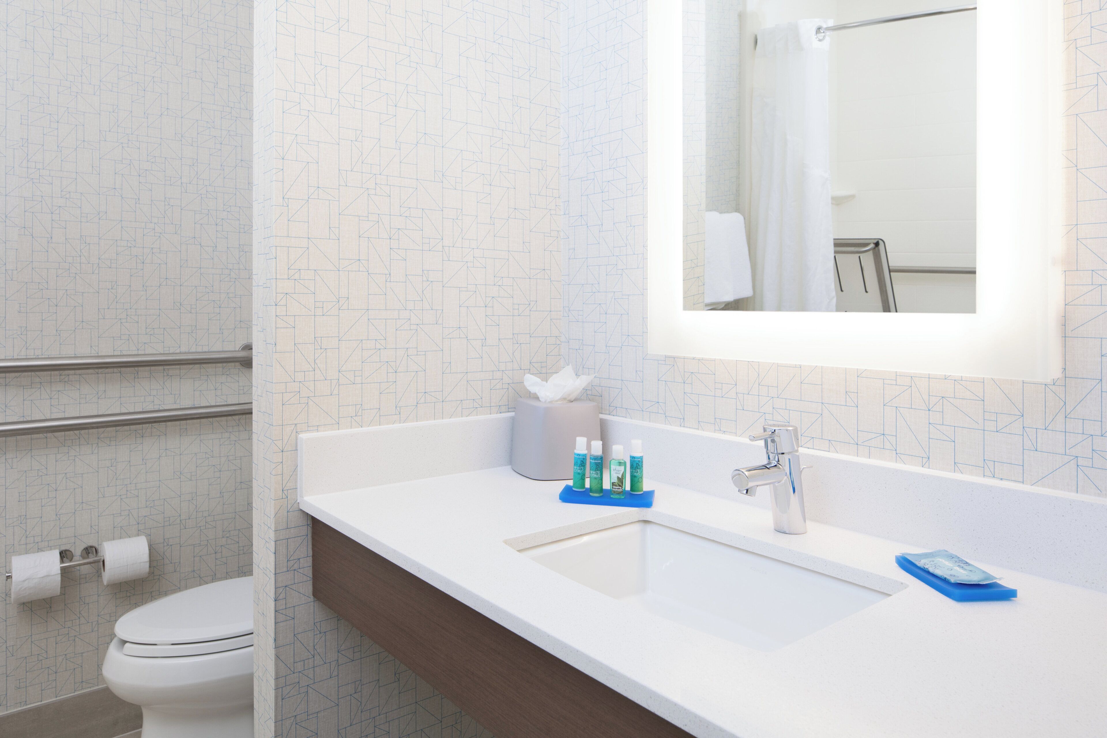 A bathroom with a white sink, a mirror, and a toilet.
