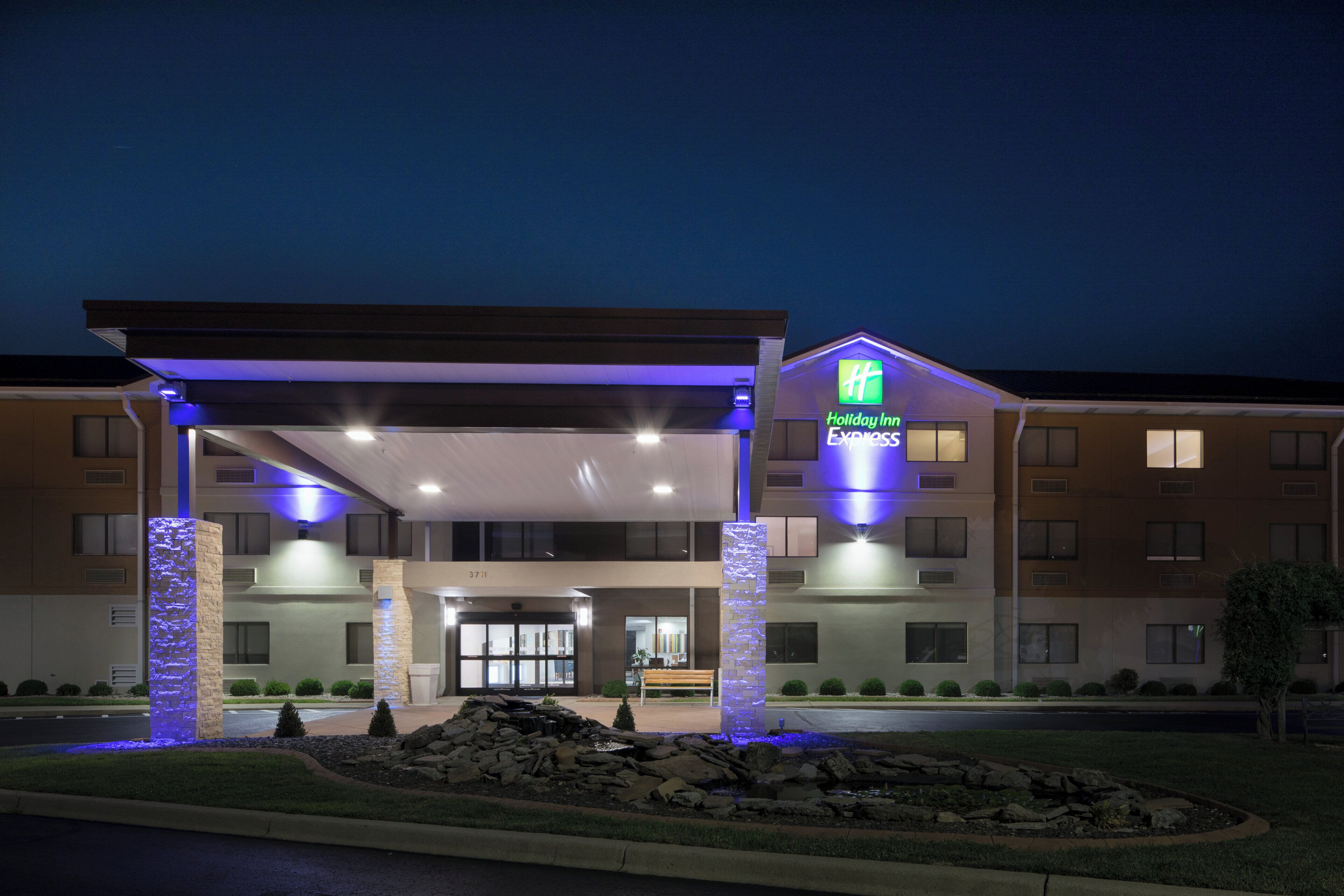 Un bâtiment de l’hôtel Holiday Inn Express doté d’une entrée abritée, de piliers en pierre et d’un espace paysager agrémenté de rochers et d’arbustes.