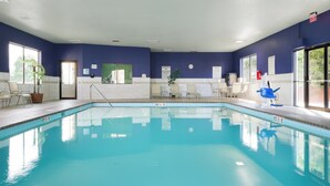 An indoor swimming pool with clear water, surrounded by lounge chairs and a potted plant. - Holiday Inn Express Louisville Northeast by IHG (Louisville)