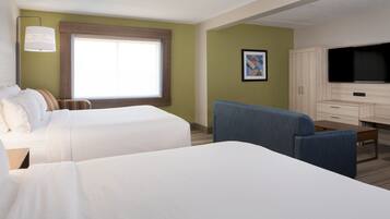 A hotel room with two beds, a desk, a chair, a television, and a window.