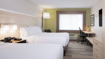 A hotel room with two beds, a desk, a chair, a desk lamp, a telephone, and a window.