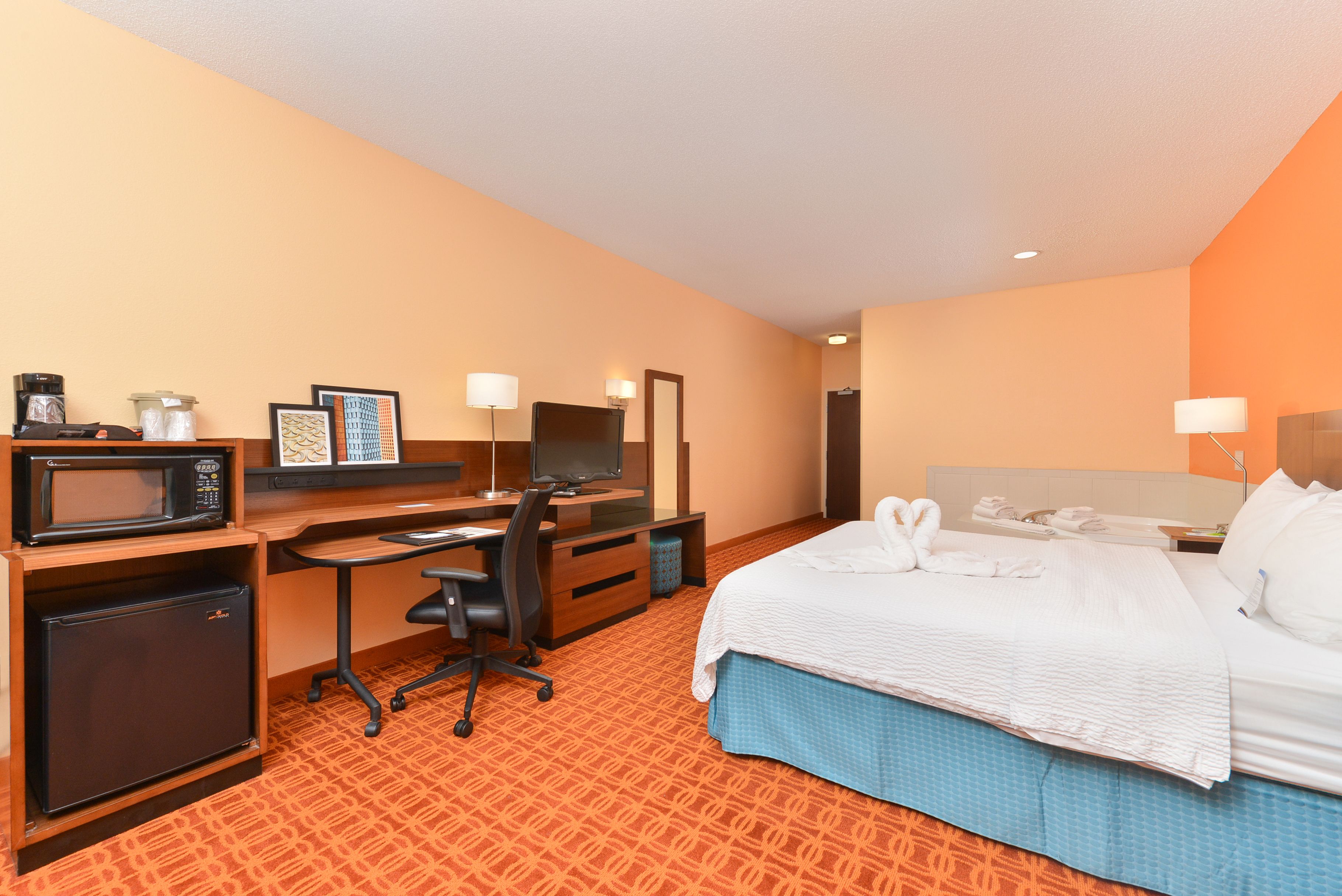 Une chambre d’hôtel équipée d’un lit, d’un bureau, d’un four à micro-ondes, d’un réfrigérateur et d’un petit coin salon.