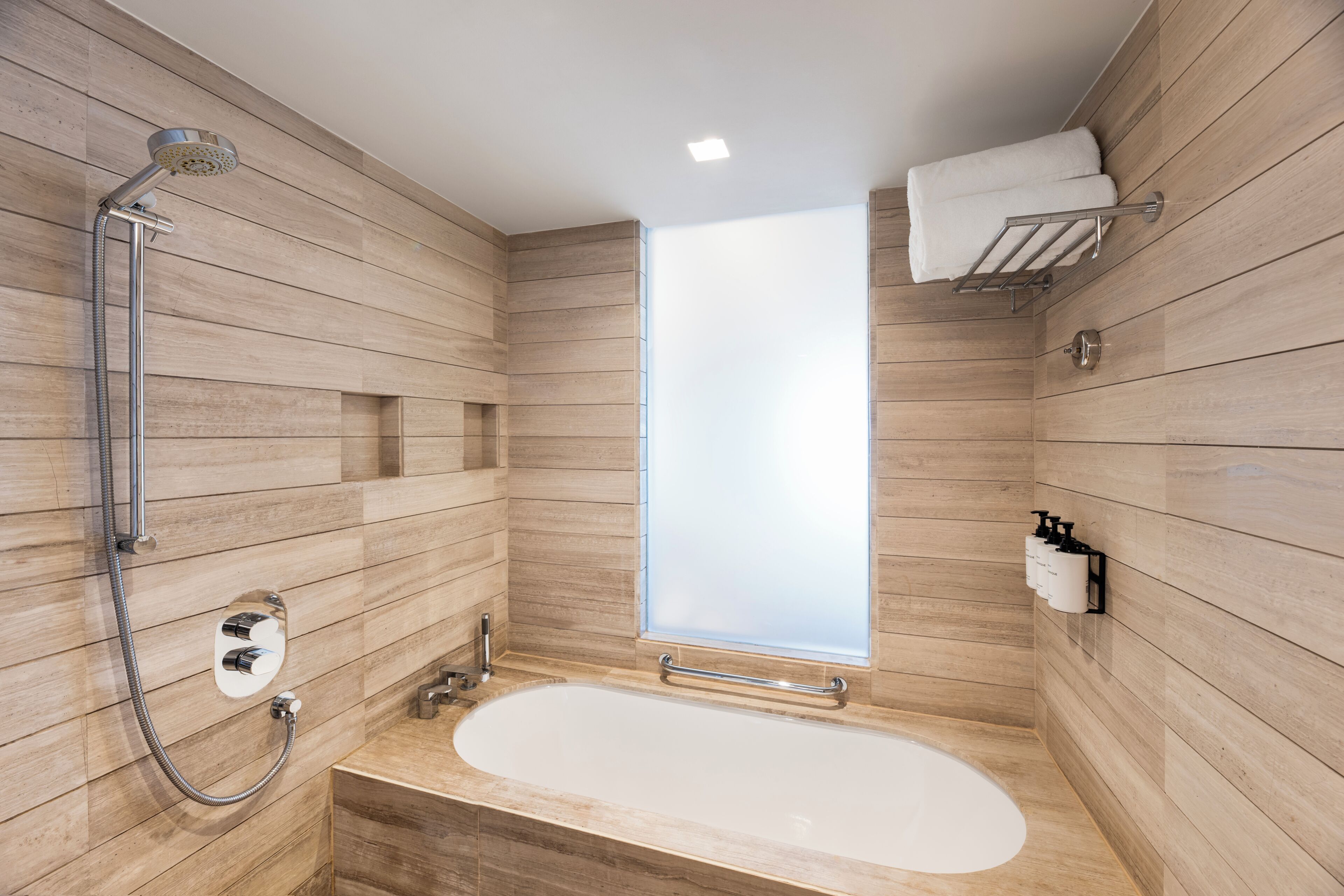 A modern bathroom with a freestanding bathtub, a showerhead, and a towel rack.