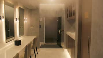 A modern bathroom with a vanity, mirror, and shower area.