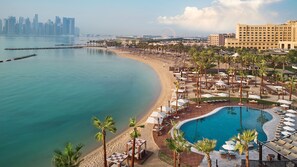 Un resort con piscina, spiaggia e sullo sfondo la linea dell'orizzonte cittadina.