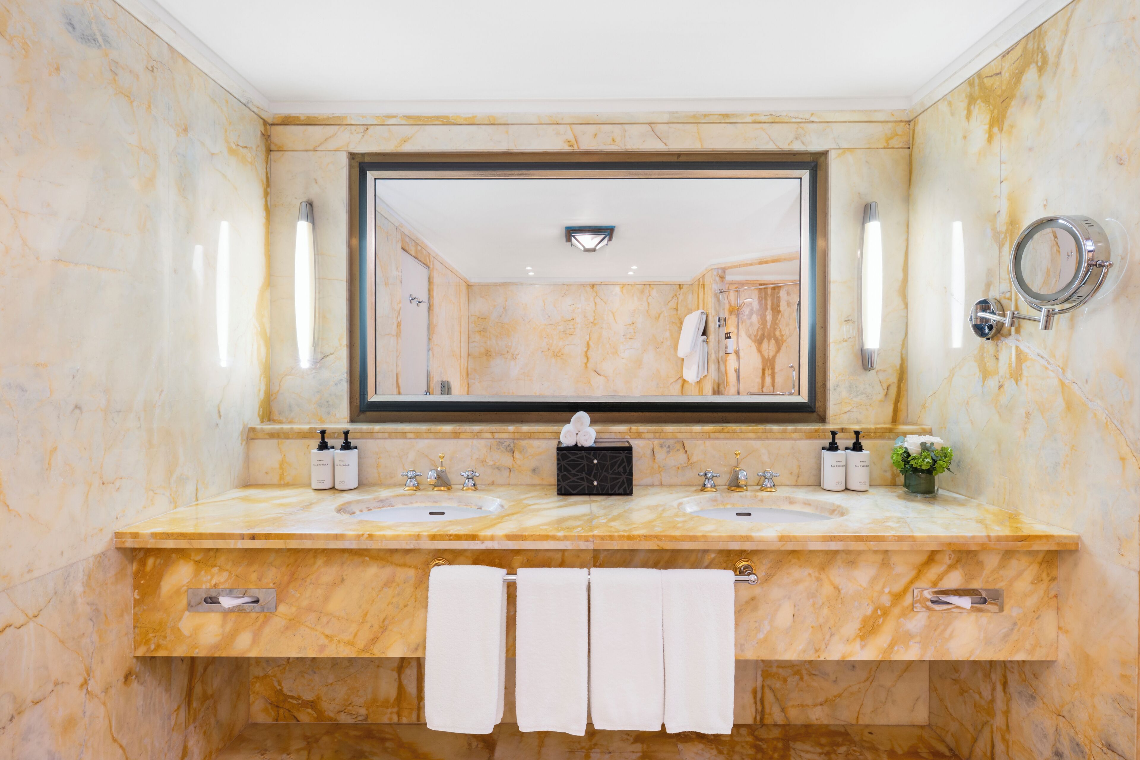 A bathroom with marble walls, two sinks, a large mirror, and a towel rack.