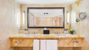 A bathroom with marble walls, two sinks, a large mirror, and a towel rack.