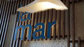 A wall with vertical wooden slats and illuminated letters spelling 'la mar'.