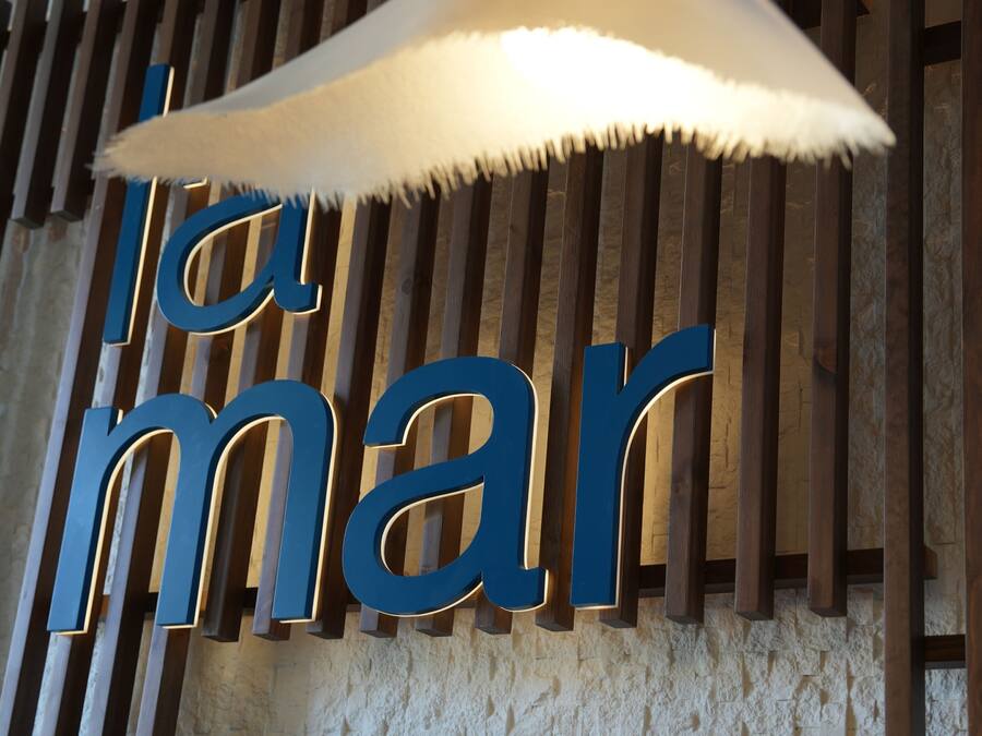 A wall with vertical wooden slats and illuminated letters spelling 'la mar'.