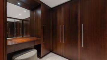 Un baño moderno con un espejo grande, armarios de madera oscura y un banco.