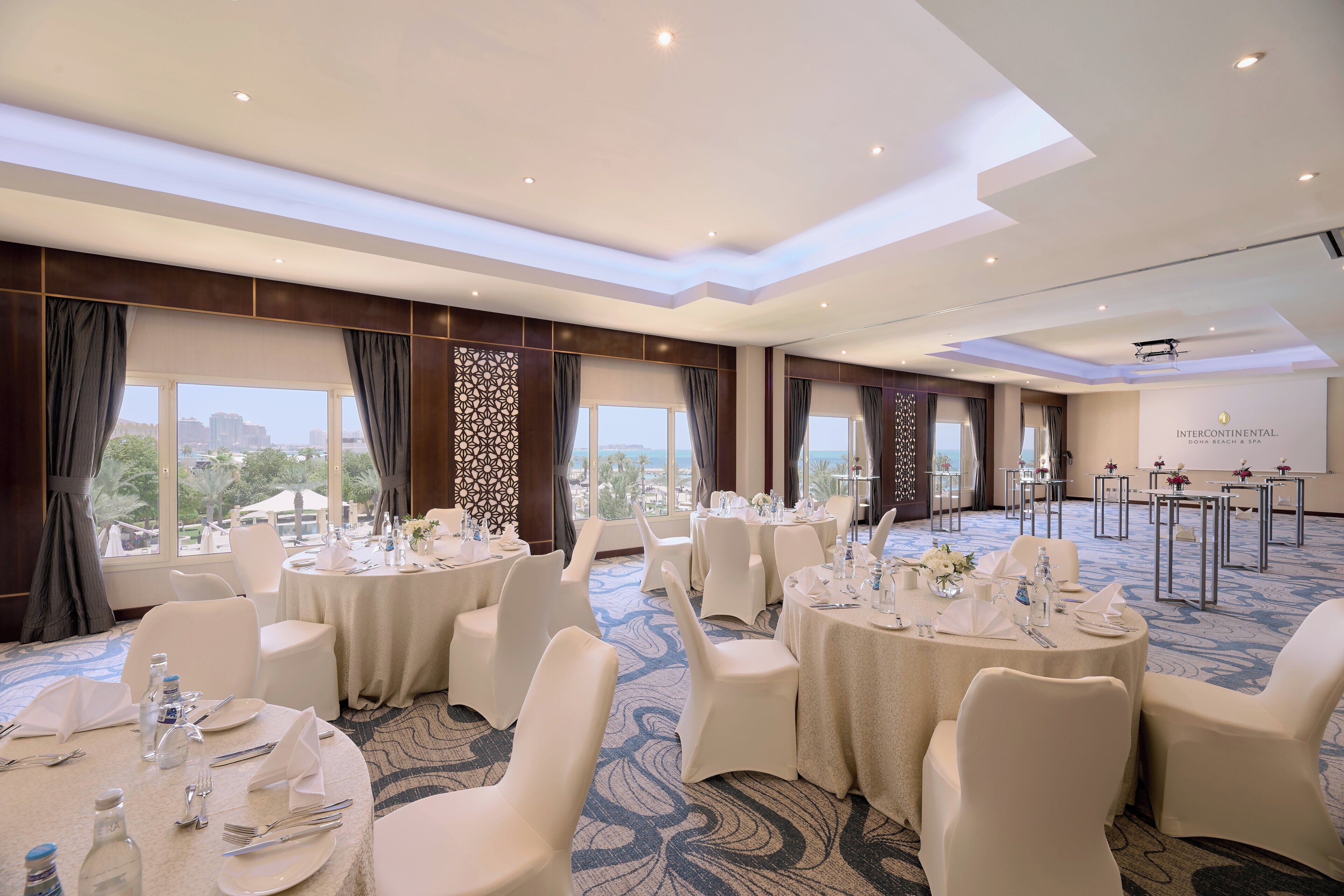 A conference room with round tables, white chairs, and a city view.