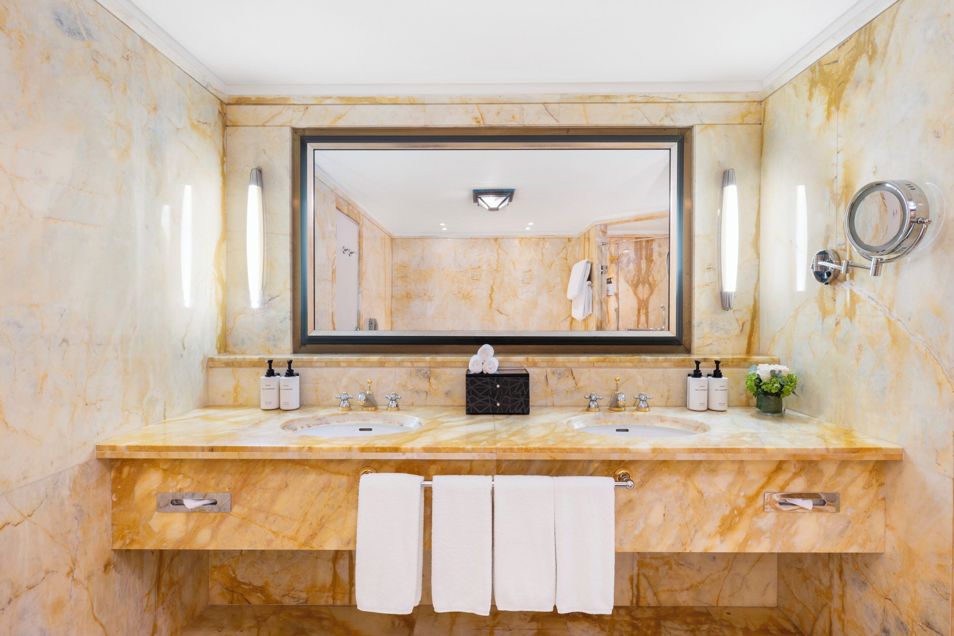 A bathroom with two sinks, a large mirror, and a towel rack.