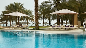 Una piscina al aire libre, sombrillas, sillones reclinables de piscina