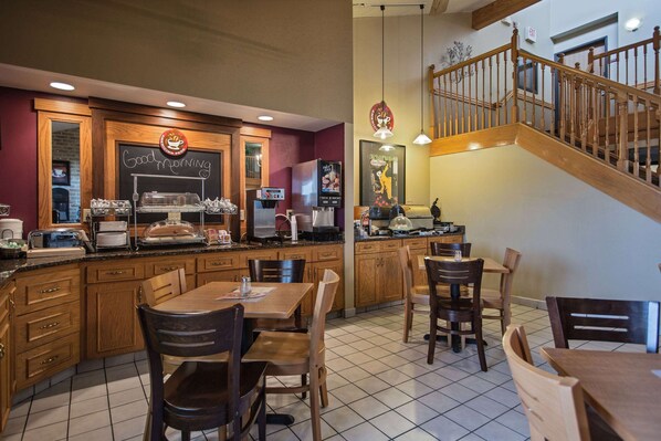 A restaurant with wooden furniture, a chalkboard menu, and a staircase.