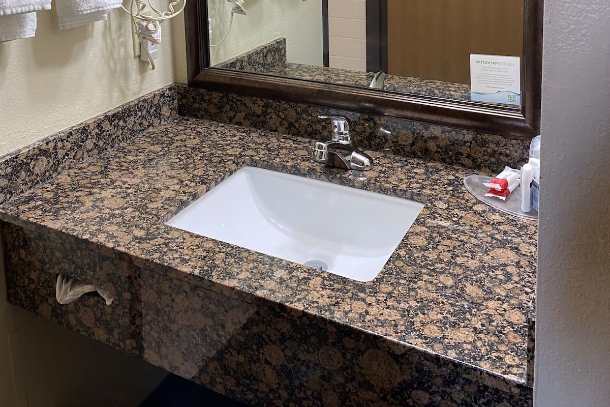 Ein Badezimmer mit Waschbecken aus Granit, einem Spiegel und Handtüchern an einem Haken.