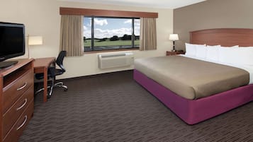 A hotel room with a bed, desk, chair, television, and a window with curtains.