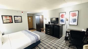 A hotel room with a bed, a desk, a TV, and a wardrobe.