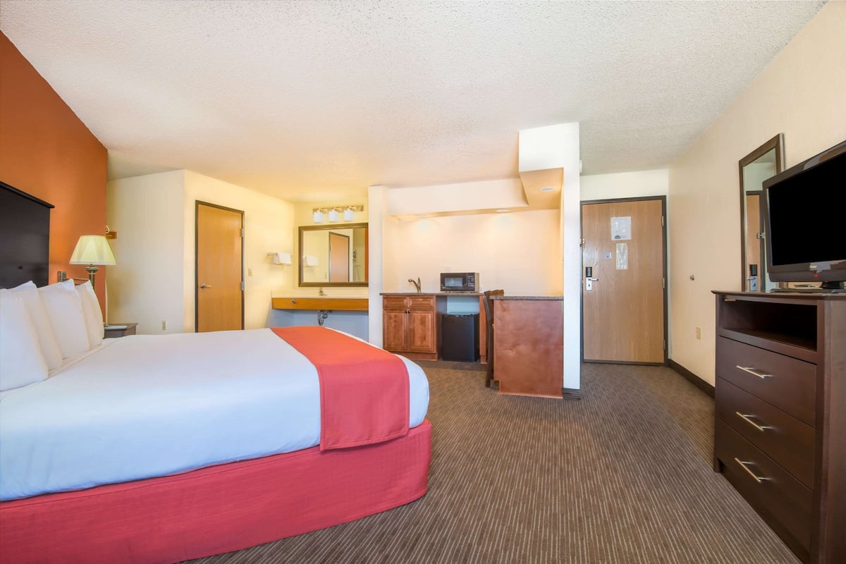 A hotel room with a bed, a desk, a television, and a mirror.