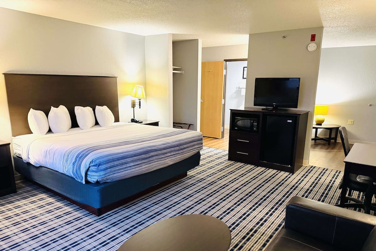 A hotel room with a large bed, a flat-screen TV, a desk, and a chair.