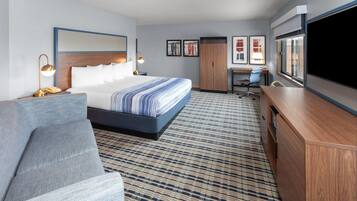 Ein Hotelzimmer mit Bett, Sofa, Schreibtisch und Fernseher.