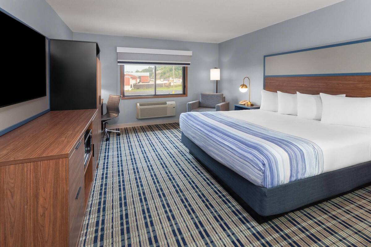 Een hotelkamer met een groot bed, een flatscreen televisie, een bureau en een stoel.