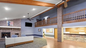 Eine geräumige Lobby mit Kamin, einer Rezeption und einer hohen Decke mit freiliegenden Balken.