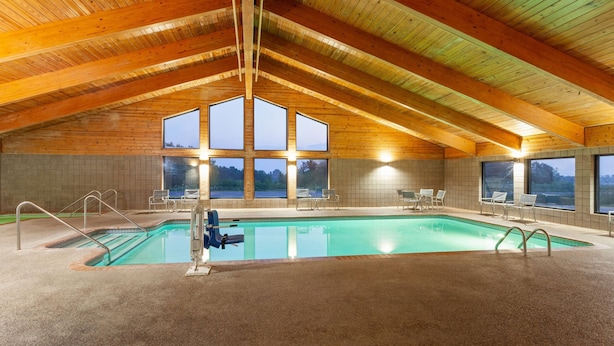 Ein Hallenbad mit hoher Holzbalkendecke und großen Fenstern.
