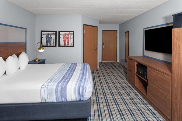 Une chambre d’hôtel équipée d’un lit, d’une télévision, d’un bureau et d’un four à micro-ondes.