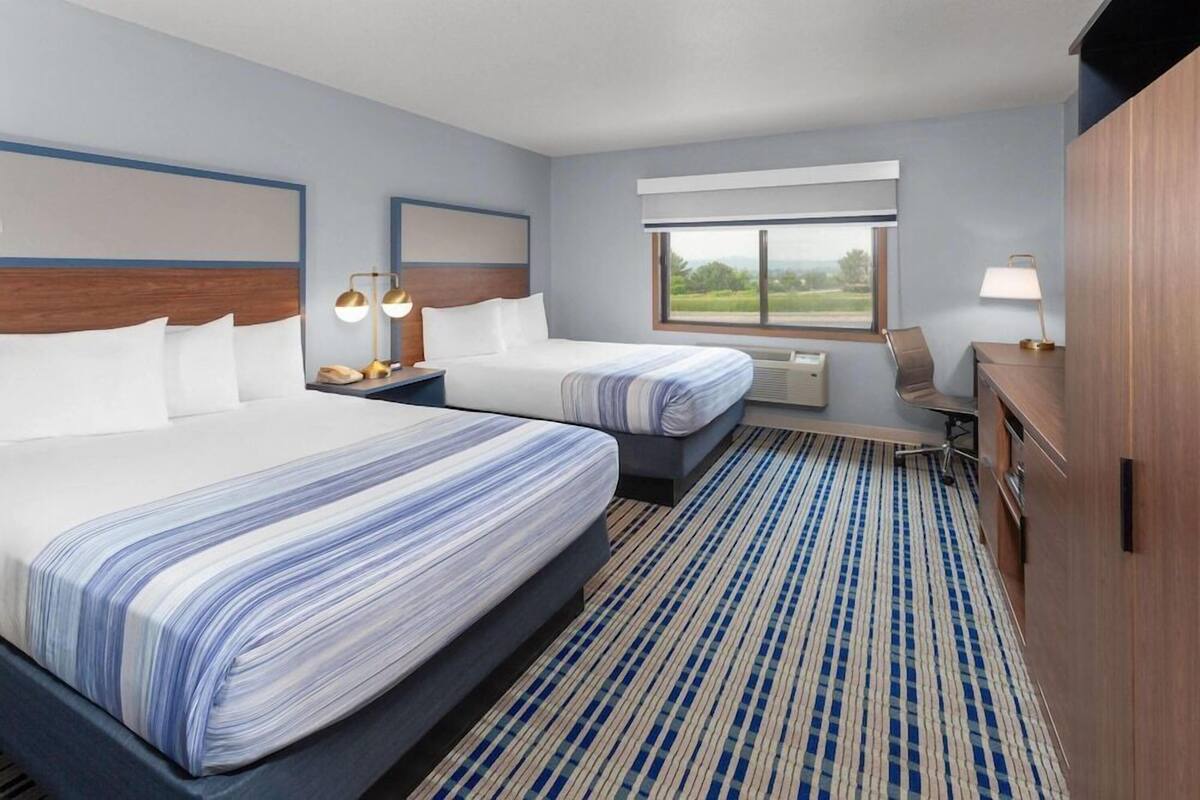 Een hotelkamer met twee bedden, een bureau, een stoel, een raam met uitzicht en een kledingkast.