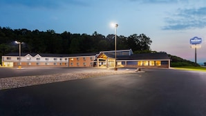 Ein Motel mit großem Parkplatz, überdachter Einfahrt und einem Schild, das einen überdachten Pool anzeigt.